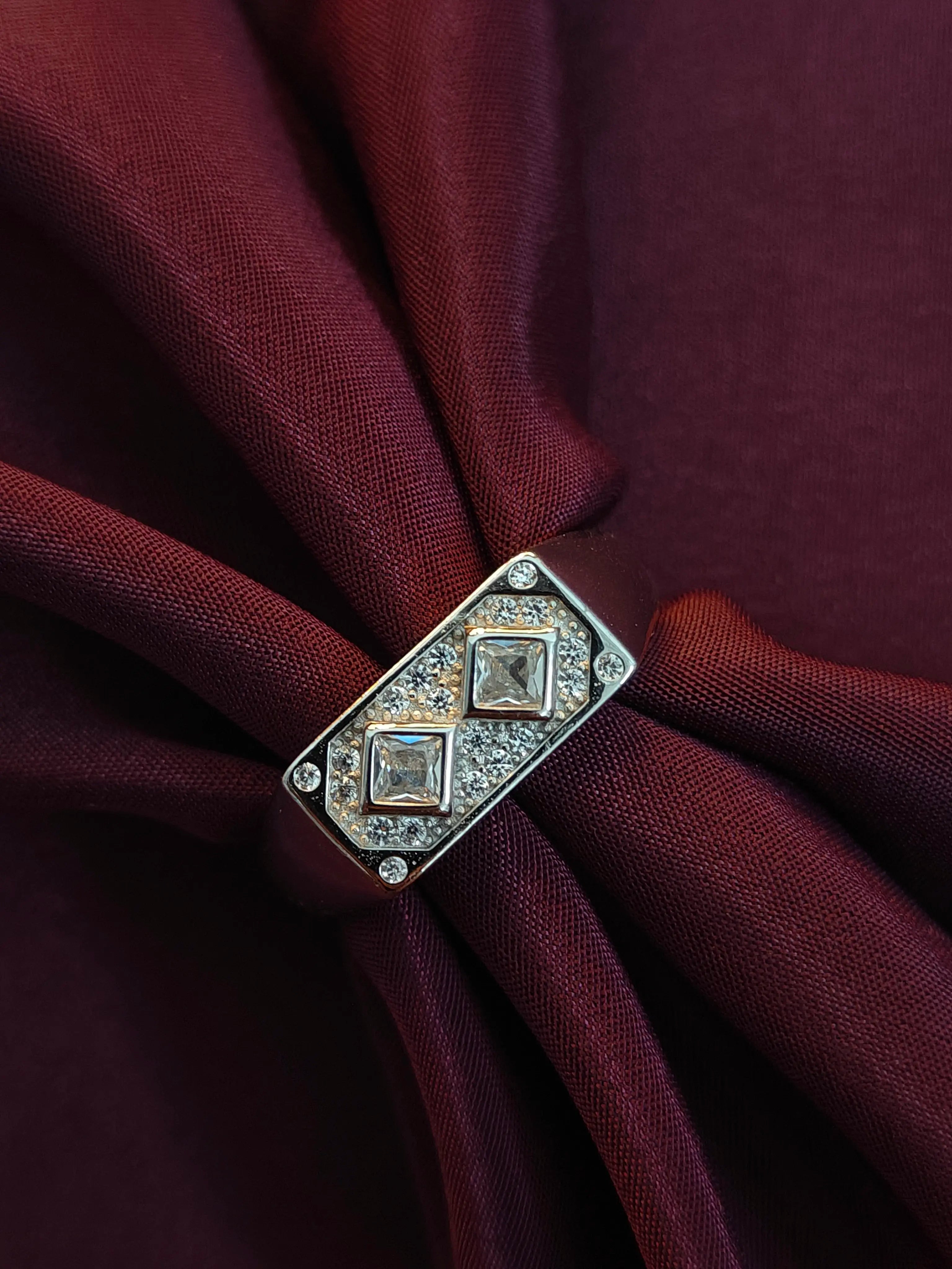Decorative brooch with gemstones on a burgundy fabric background